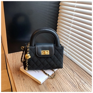 Detailed macro view of black quilted crossbody bag with gold hardware and metal ball charm