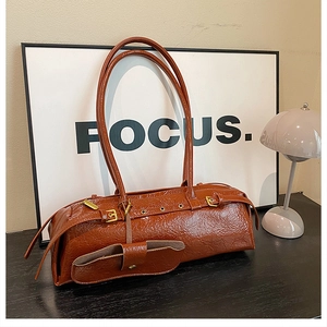 Close-up of caramel brown wrinkled leather shoulder bag with gold buckles and small pouch