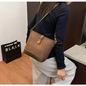 Detail view of brown vintage bucket bag featuring gold metal lock and adjustable strap