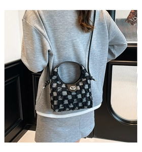 Detail of checkered denim bucket bag with distressed fringe and silver metal clasp
