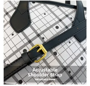 Detail of adjustable black leather strap with gold buckle on plaid bucket bag