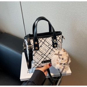 Detail of checkered crossbody bag with plush bunny charm and XIYOU SHIJIA metal plaque