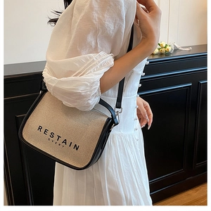 Detail of oatmeal canvas and black leather crossbody bag on a white dress model
