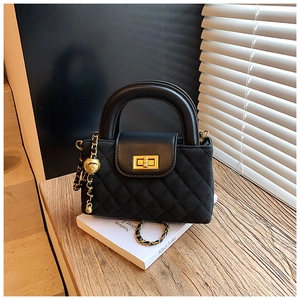 Detail of black quilted leather handbag with gold twist lock and chain strap on books