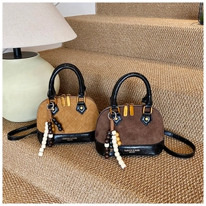 Detail of mini shell bags with quilted suede and smooth leather handles in a cozy room