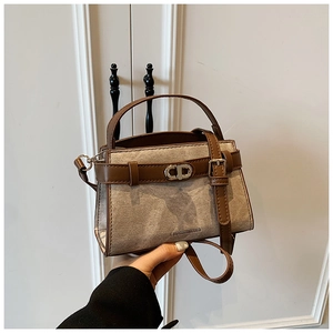 Detail view of stylish crossbody bucket bag with brown leather trim and metallic CD buckle