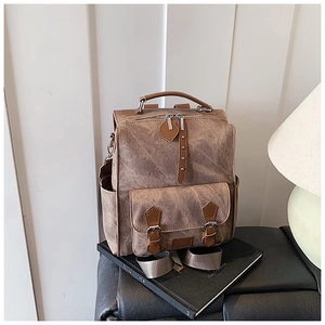 Close-up of vintage brown backpack featuring classic buckle straps and metal rivet details