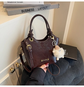 Close-up of retro dark brown bucket bag with glossy crinkle texture and cute lamb charm