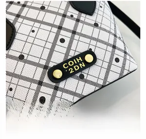 Macro detail of the plaid bucket bag showing textured lychee leather and gold hardware