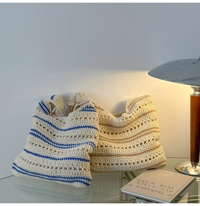 Detail of hollow knit shoulder bags with blue and brown stripes on glass table