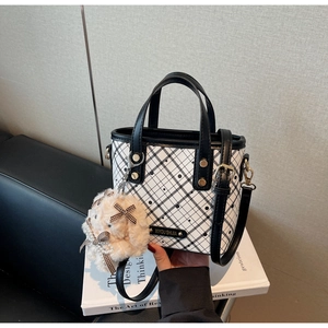 Close-up of contrast checkered bucket bag featuring gold logo and plush bunny charm