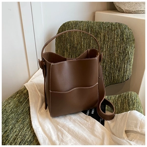 Detailed top view of dark brown leather bucket bag on vintage chair showing soft texture