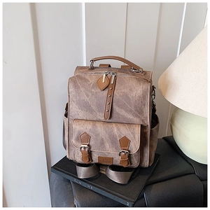 Detail of vintage brown faux leather backpack with retro straps on a leather seat