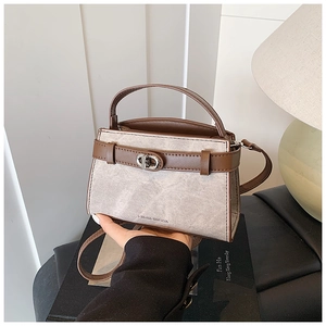 Close-up of light gray textured bucket bag with brown PU trim and metallic twist lock