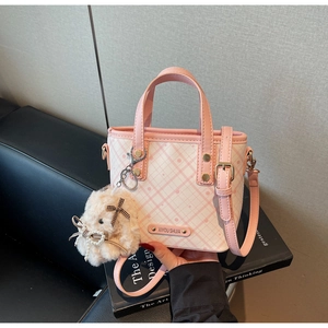 Detail of pink and white checkered bucket bag with plush rabbit charm and shoulder strap
