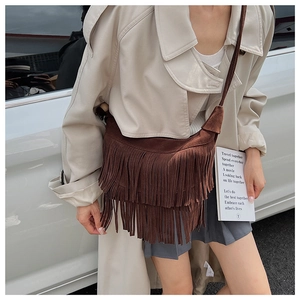 Close-up of vintage brown suede crossbody bag with long fringes in outdoor setting