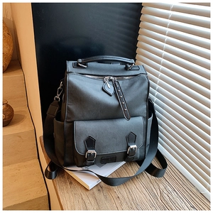 Detail of dark grey PU leather backpack showing flap front pocket and textured finish