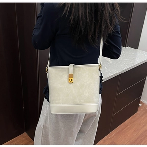 Detail view of cream bucket bag with gold twist lock and adjustable shoulder strap