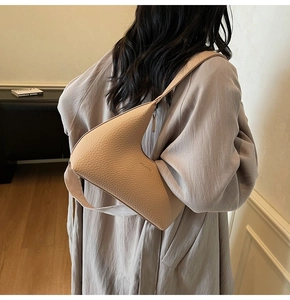 Chic beige dumpling shoulder bag featuring pebble leather on model for size perspective