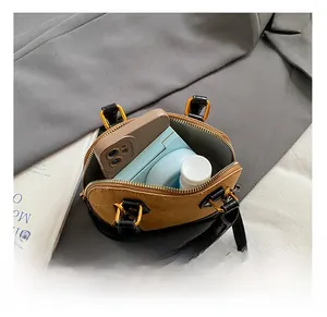 Interior view showing the capacity of a tan shell bag with smartphone and cosmetics