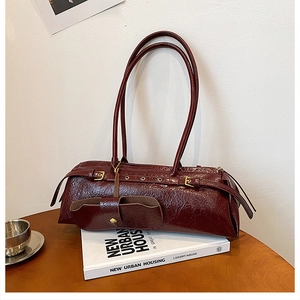 Close-up of deep red vintage leather baguette bag with buckle and gold hardware