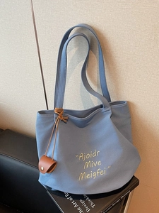 Minimalist light blue canvas tote bag with letter print and brown leather charm