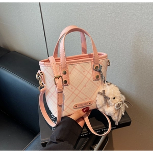 Detailed close-up of pink and white checkered bucket bag with plush bunny charm
