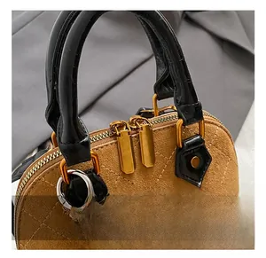 Detail showing high-end brown shell bag with black patent leather handle and gold hardware