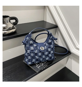 Detailed close-up of distressed denim checkerboard bucket bag with silver metal twist lock