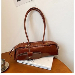 Detail of vintage brown baguette bag with double straps and detachable mini pouch on book