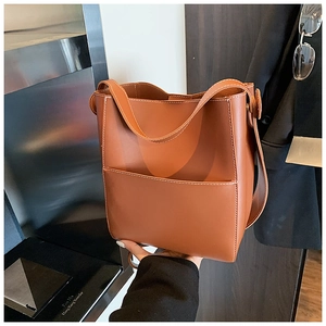 Close-up of caramel leather bucket bag featuring white contrast stitching and front pocket
