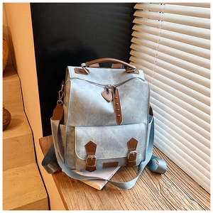 Close-up of light blue vintage backpack with brown leather accents on a wooden base