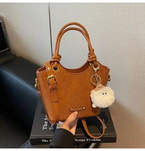 Detail view of retro brown leather bucket bag with metal rings and plush charm
