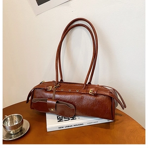 Detail of dark brown vintage Boston bag with oil leather texture on a book