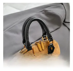 Detail of khaki quilted suede shell bag with black leather handles and gold zippers