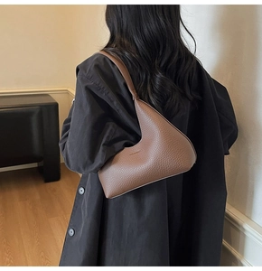 Detail of brown pebbled leather shoulder bag with unique geometric shape and logo