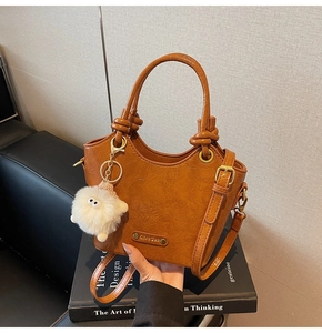Close-up of embossed leather texture on a vintage brown bucket bag with plush charm