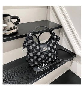 Detail of checkered bucket bag featuring silver twist-lock and premium leather strap