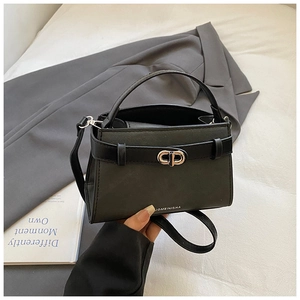 Close-up of matte black bucket bag with silver metal ring buckle and leather belt detail