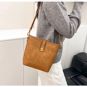 Detailed view of caramel suede bucket bag featuring smooth leather trim and metal clasp