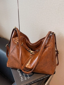 Vintage brown leather tote bag with gold buckles placed on books for casual commute