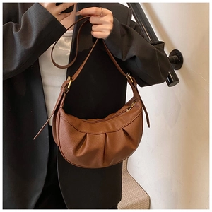 Détail du sac demi-lune plissé marron avec zip doré et texture en similicuir lisse