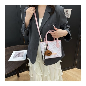 Detail of pink plaid bucket bag featuring plush puppy charm and striped scarf accessory