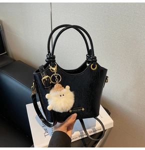 Detailed view of black pleated bucket bag with gold hardware and white sheep charm