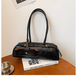 Detail of black wrinkled leather hobo bag with gold buckle accessory and dual straps
