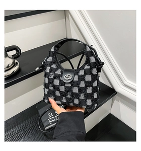 Detail of checkered denim bucket bag featuring frayed edges and silver metal twist lock