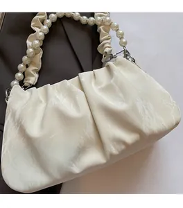 Détail du sac nuage froncé crème avec anse en perles et texture de tissu doux sur veste