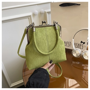 Detail of green faux suede kiss-lock handbag with metal frame and circular handle