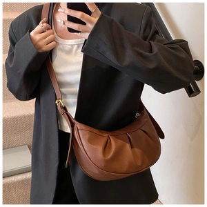 Détail d'un sac bandoulière demi-lune plissé marron avec boucle dorée et sangle réglable