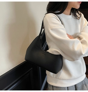 Detail of black lychee grain leather hobo bag showing texture and slim shoulder strap